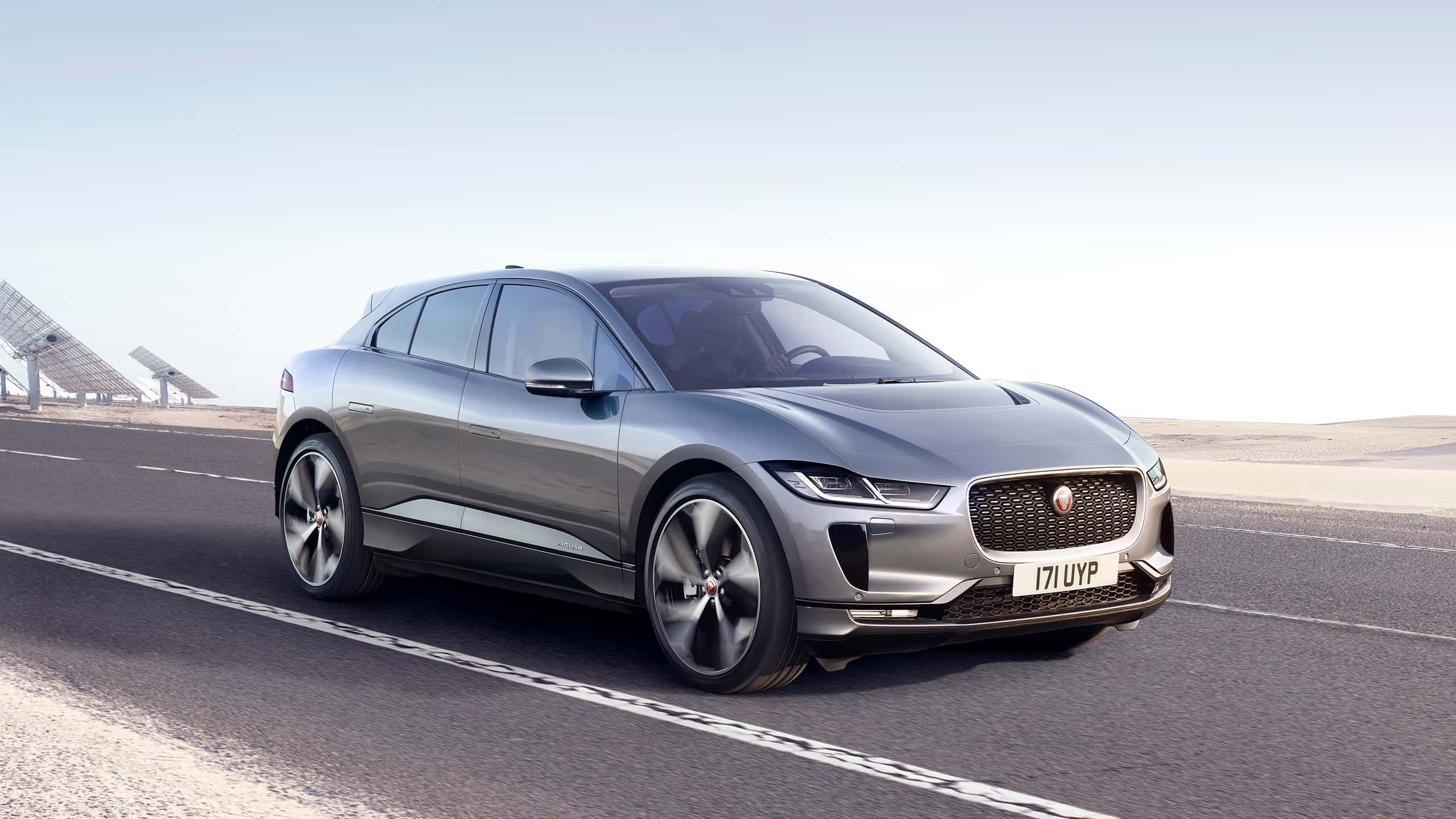 Jaguar I-Pace running on the road and with solar power plant background 